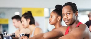Four people working out in the LSBU gym, with one guy in a red vest looking at the camera.